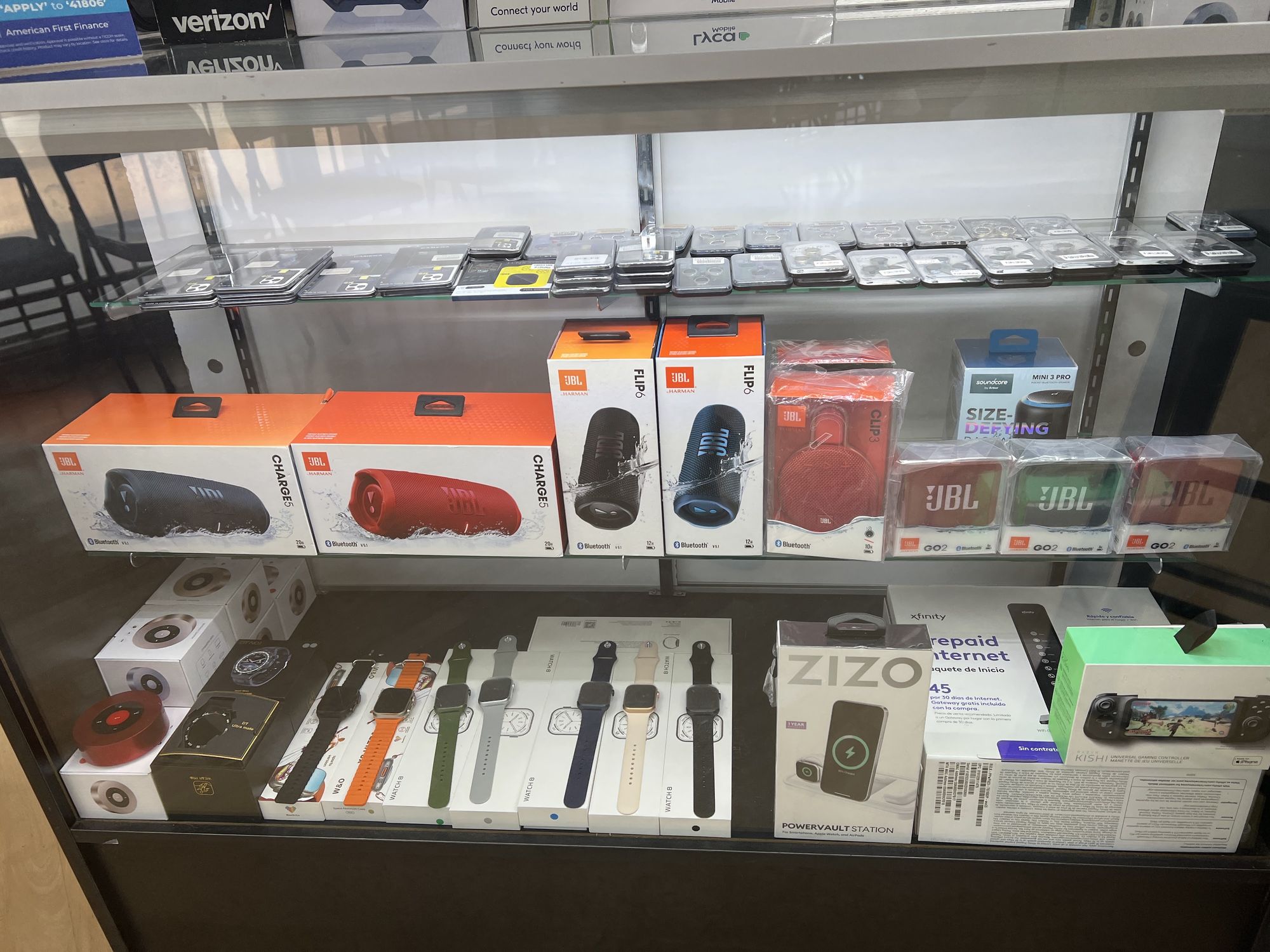 JBL speakers, smartwatches and wireless chargers in a display case